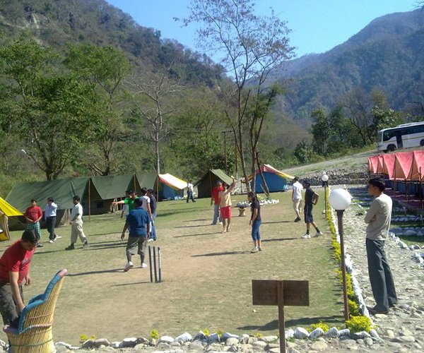 A group playing cricket as a activity in camping